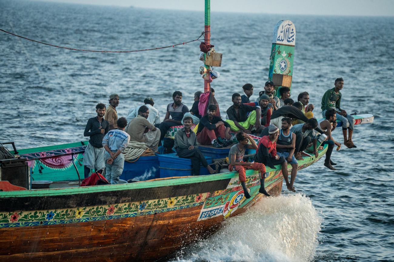 A colorful traditional fishing boat with a crew navigating the sea, showcasing cultural and marine life.