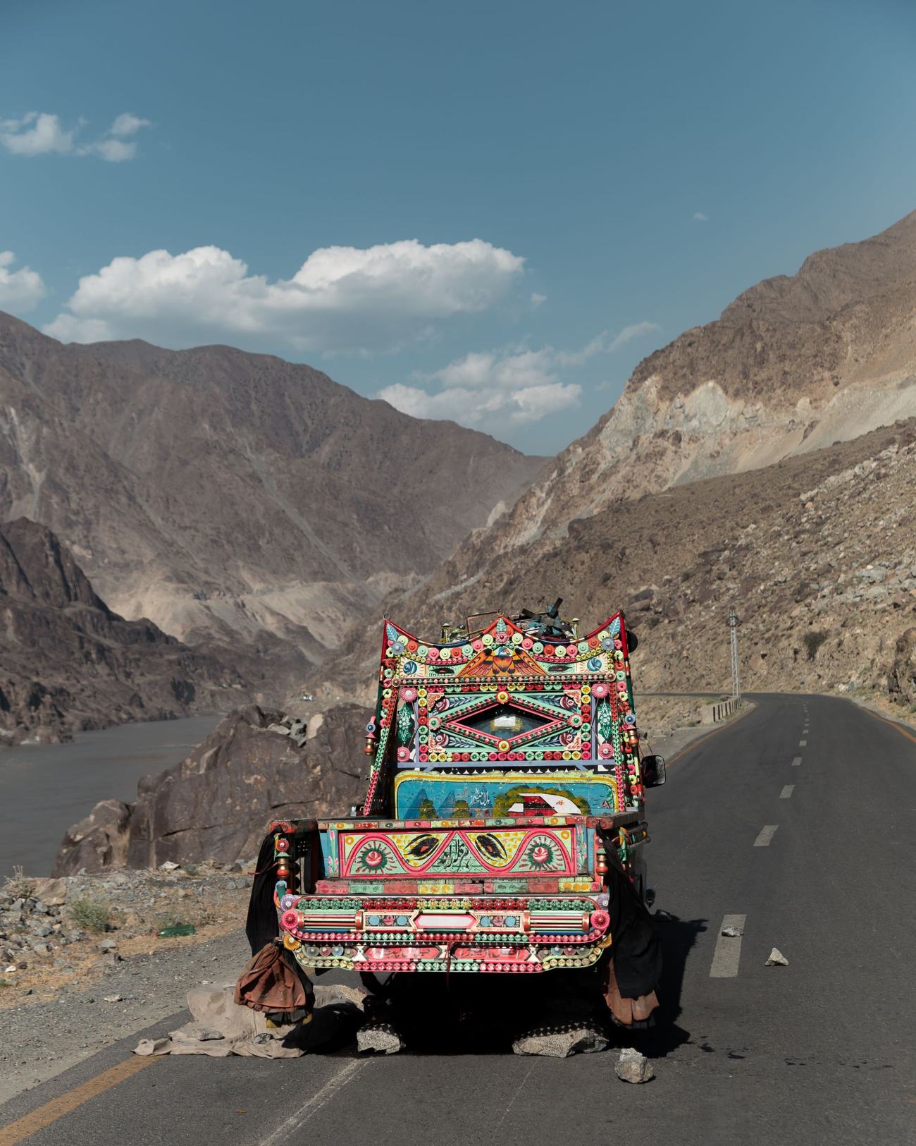 Decorated truck on the scenic Karakoram Highway surrounded by mountains in Pakistan.